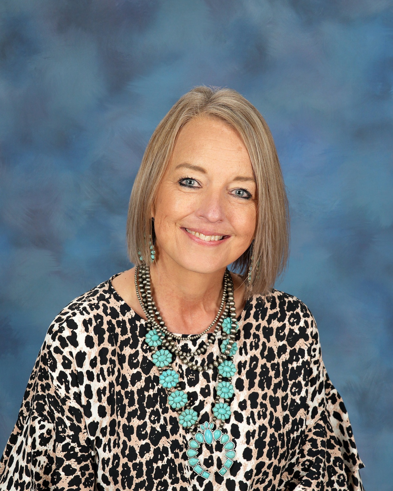 A woman with blonde hair and glasses smiles at the camera.